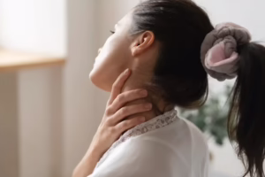 Female in white shirt holding neck due to severe neck pain