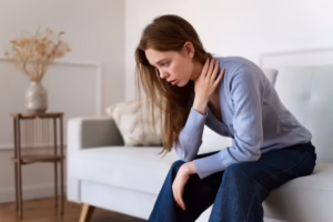 Woman sitting on couch experiencing chronic body pain
