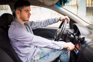 Person experiencing lower back pain while sitting in a car